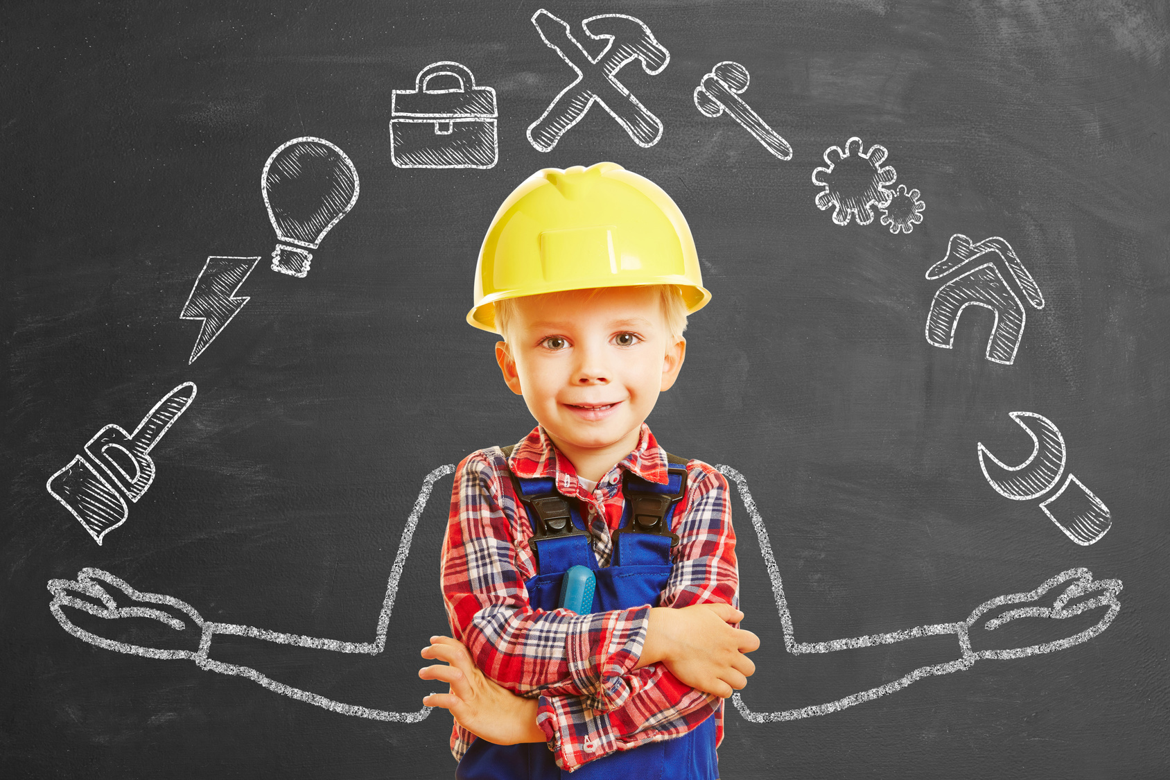 Enfant déguisé en ouvrier du bâtiment devant un tableau noir avec des dessins à la craie liés au monde du travail