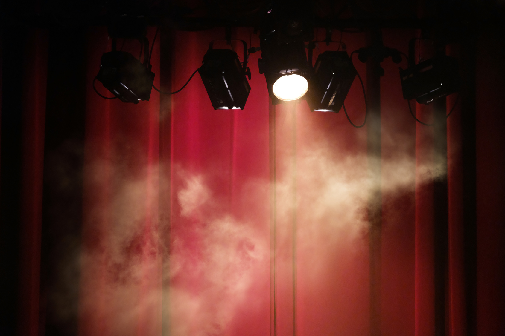 Projecteurs et fumée devant un rideau rouge